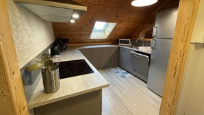 Eine kompakte Küche mit Holzbalkendecke, Oberlicht und modernen Geräten, darunter eine Mikrowelle und ein Kühlschrank.