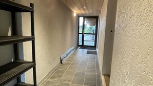 Ein Flur mit Holzbalken an der Decke, Fliesenboden und einem schwarzen Metallregal.