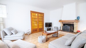 Un saló amb una llar de foc, dos sofàs, una taula de centre i una televisió.