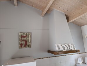 Et moderne badeværelse med træloft, en hvid vask og et skilt med teksten 'HOME' over vasken.