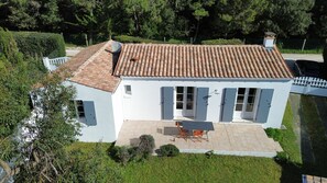 Ein weißes, zweistöckiges Haus mit Ziegeldach, überdachter Terrasse und umzäunter Garten.