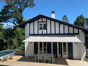 Une maison à deux étages dotée d’un patio couvert, d’une piscine et d’un coin repas.