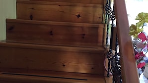 Un escalier en bois doté d’une rampe et d’une volute décorative en métal.