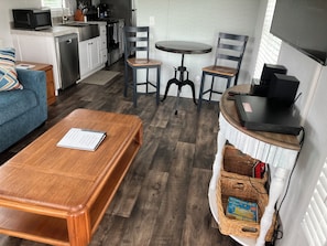 A compact living space with a kitchenette, a dining area with a round table and two chairs, a sofa, and a wooden coffee table.