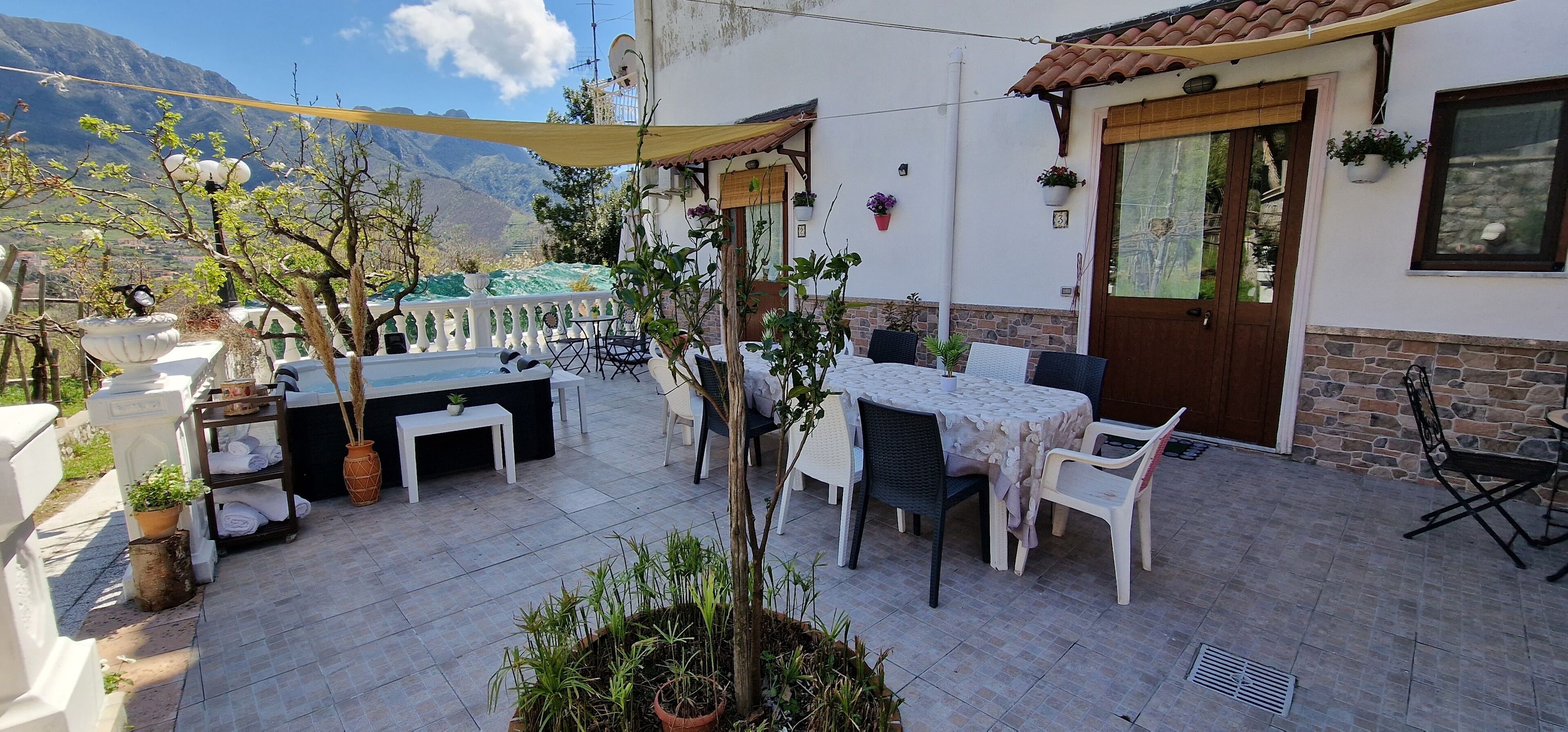 A patio with outdoor furniture, a white table with a lace tablecloth, and potted plants.