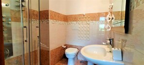 A modern bathroom with a glass shower enclosure, a white toilet, and a large sink with a mirror above it.