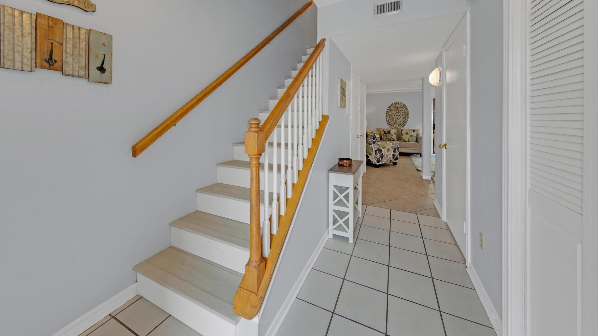 A staircase with wooden handrails and white steps leading to a living area with a sofa and a coffee table.