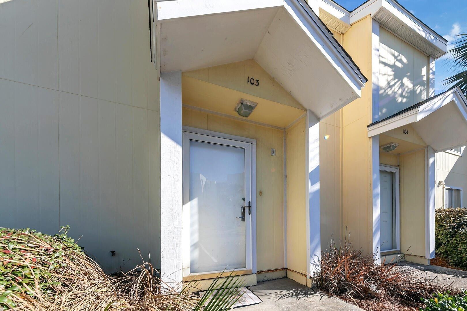 A building with numbered doors, a concrete entrance, and some vegetation around.