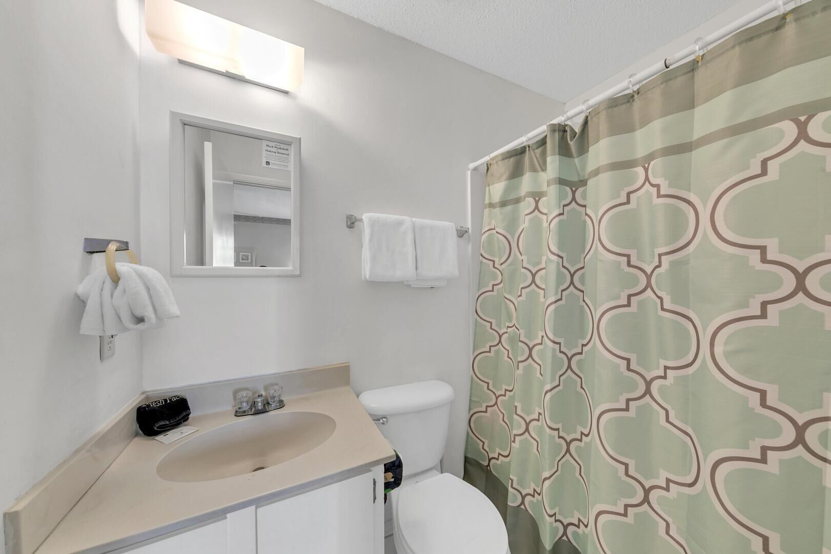 A bathroom with a toilet, sink, and a shower curtain with a geometric pattern.