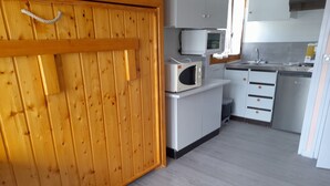 Moderni keittiö, jossa on puiset kaapit, mikroaaltouuni, pesuallas ja työtaso.