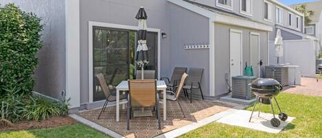 A patio with a table and chairs, a grill, and a covered area with an umbrella.