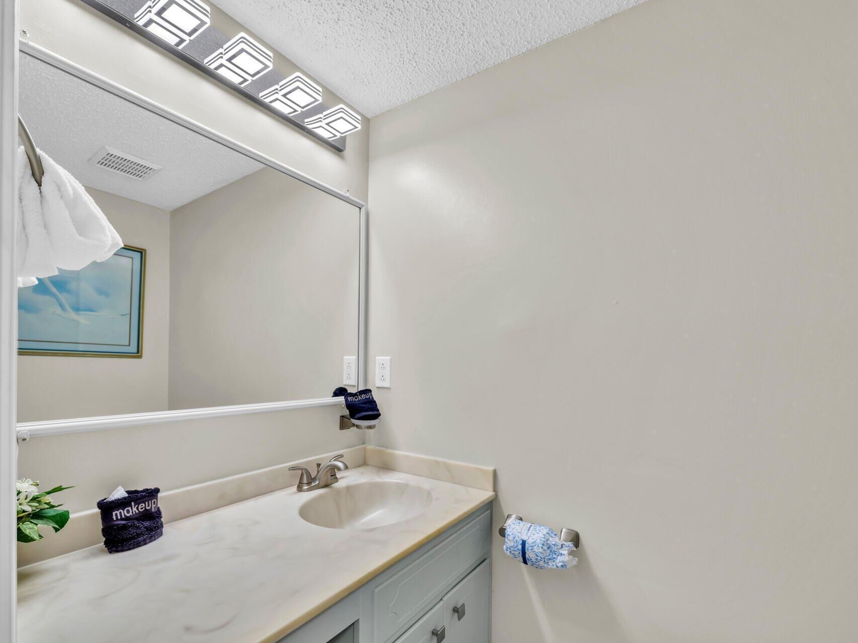 Une salle de bain avec un grand miroir, un lavabo et un porte-serviettes.