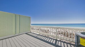 Une terrasse en bois avec une balustrade blanche donnant sur une plage.