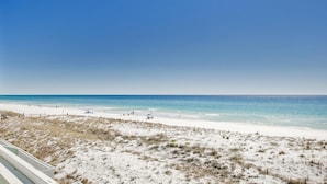 A beach with white sand and clear blue water. There are people and beach umbrellas visible. - Southbay by the Gulf 124 (Destin)