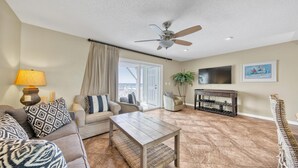 A living room with a sofa, coffee table, TV stand, and a ceiling fan. - Southbay by the Gulf 124 (Destin)