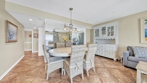 A spacious dining area with wicker chairs, a round table, and a ceiling fan. - Southbay by the Gulf 124 (Destin)