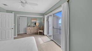 Ein Schlafzimmer mit einem Bett, einem Schminktisch, einem Stuhl und einer Glastür zum Balkon.