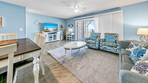 Ein Wohnzimmer mit Essbereich, Deckenventilator und Meerblick durch eine Schiebetür.