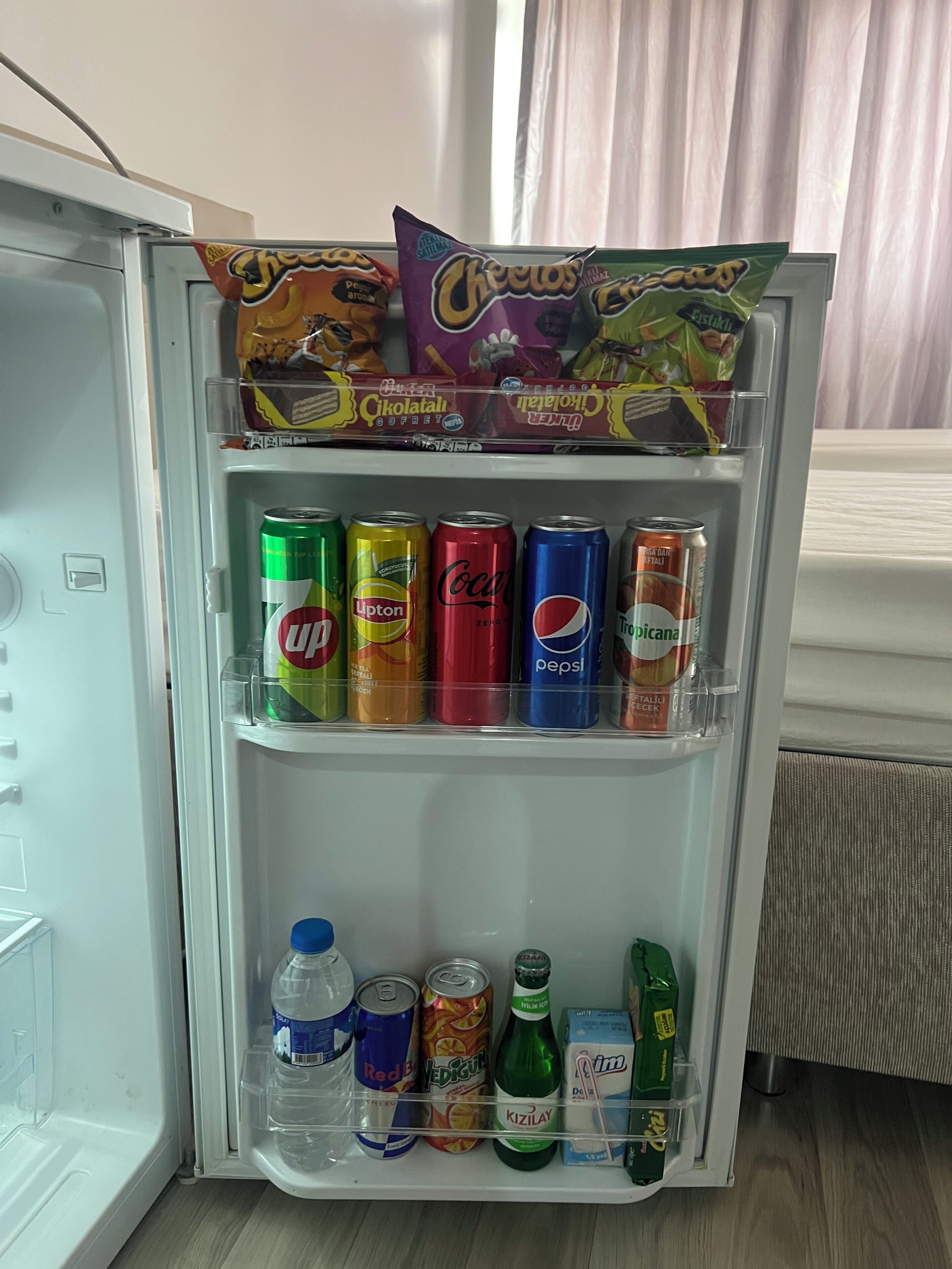 Een koelkast gevuld met verschillende drankjes en lekkernijen.