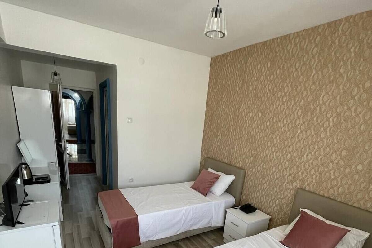 A hotel room with two beds, a desk, and a wardrobe.