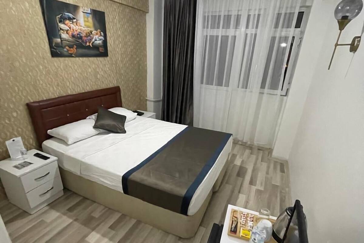 A hotel room with a bed, bedside table, and a desk with a chair.