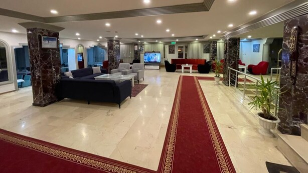 A spacious lobby with a red carpet, marble flooring, and modern seating arrangements.