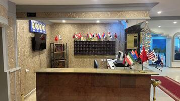 A reception area with a marble counter, a television mounted on the wall, a shelf with flags, and a sign indicating the room type.