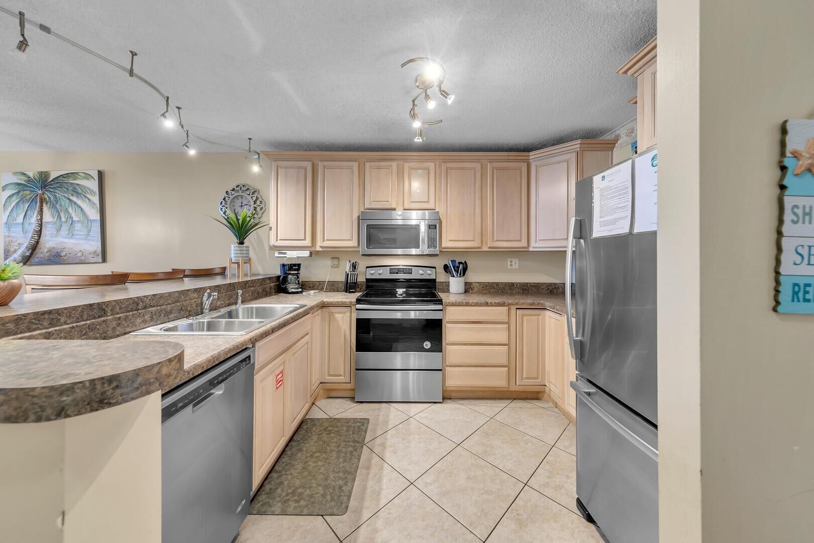 A modern kitchen with granite countertops, stainless steel appliances, and light wood cabinets.