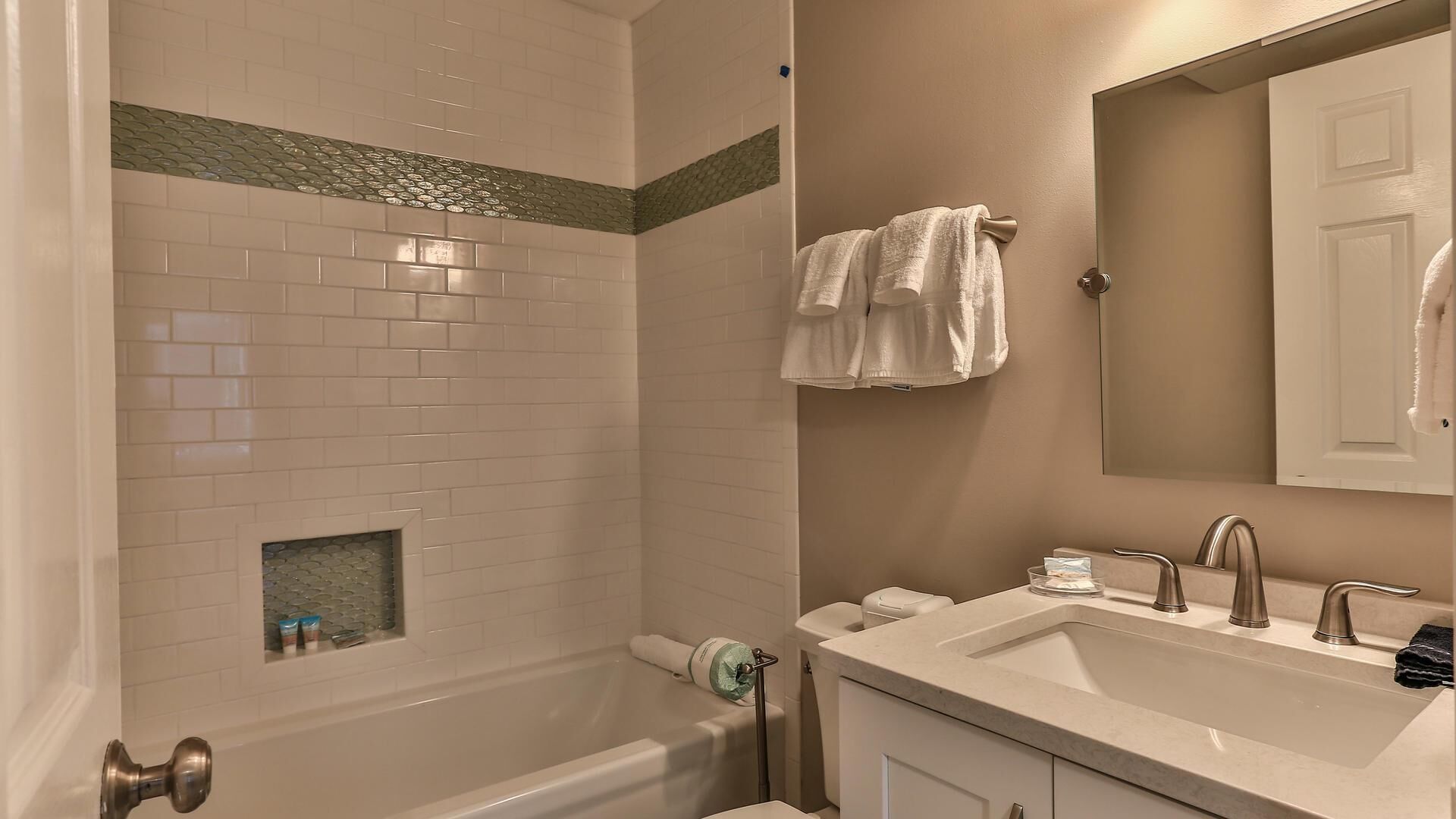 A bathroom with a bathtub, a sink, and a mirror.