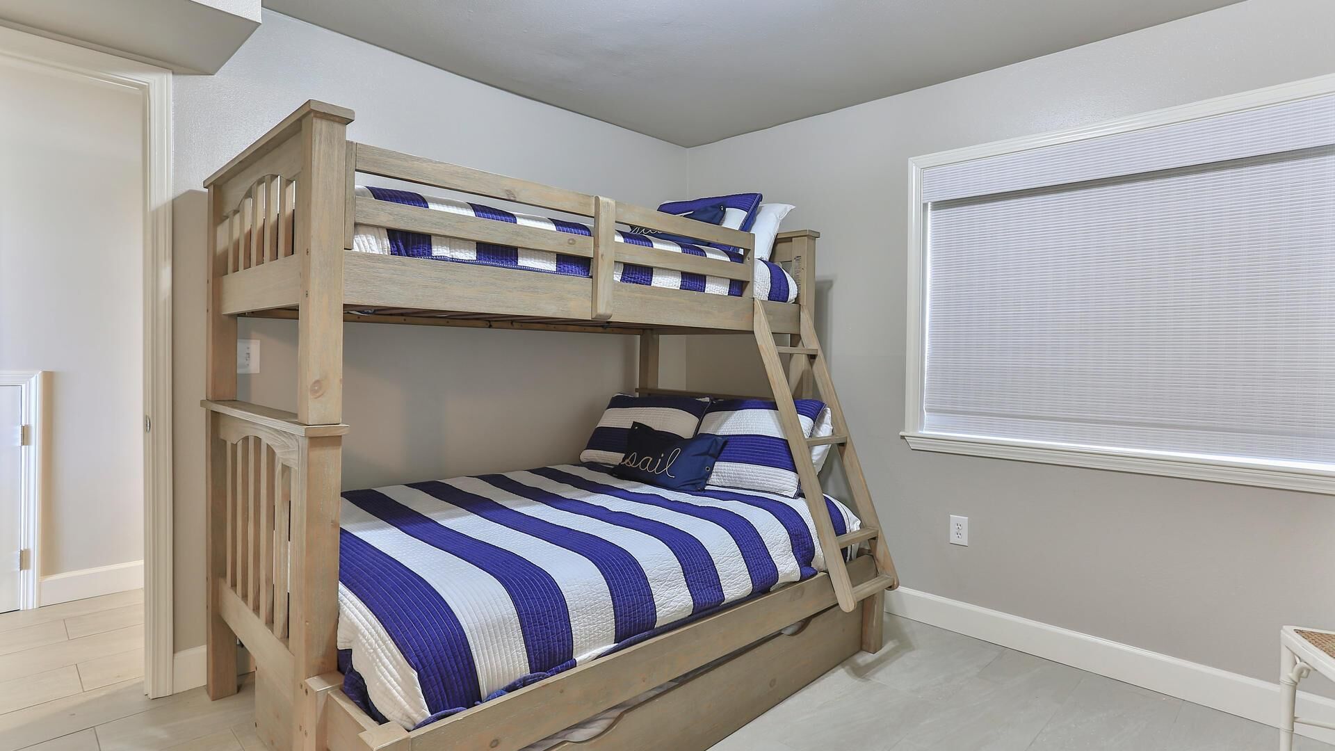 A bunk bed with a wooden frame, striped bedding, and a ladder.