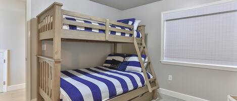A bunk bed with a wooden frame, striped bedding, and a ladder.