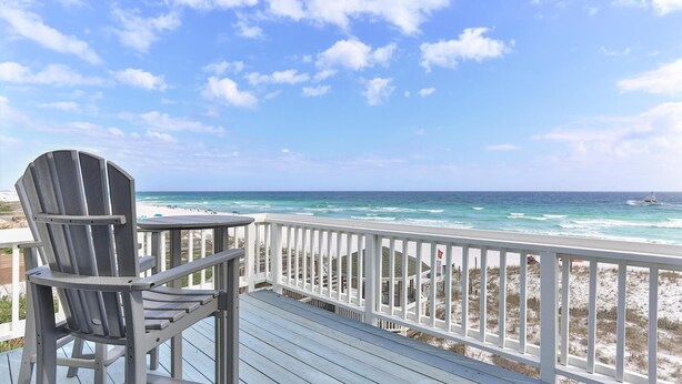 Eine Holzterrasse mit Blick auf den Ozean und den Strand.