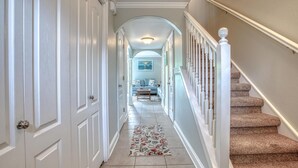 A hallway with a carpet, a staircase, and a painting on the wall.
