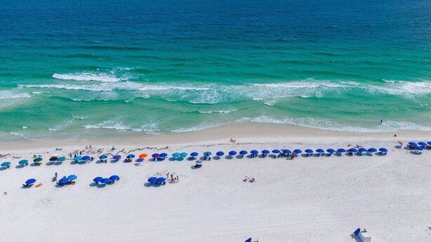 A beach with a row of umbrellas and people.