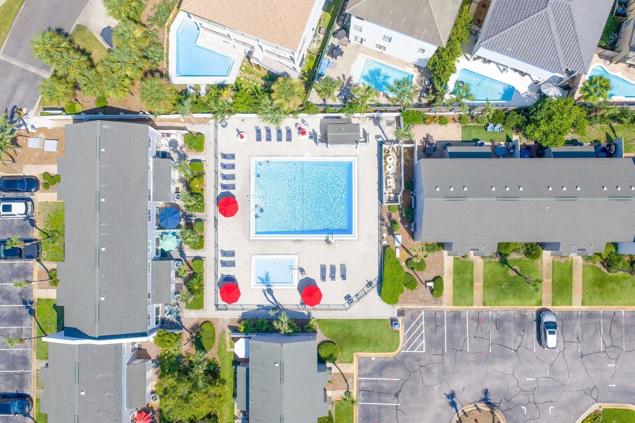 Eine Luftaufnahme einer Anlage mit mehreren Schwimmbecken, einem Parkplatz und umliegender Bepflanzung.