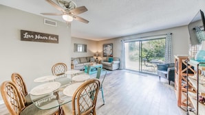 A spacious living room with a dining area, a ceiling fan, and a large window offering a view of the outdoors. - Southbay by the Gulf 34 (Destin)