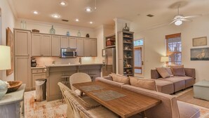 A compact living space with a kitchenette, a dining area, and a seating area with a sofa and a chair. - Conch Cottage (Santa Rosa Beach)