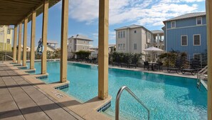 A swimming pool with a covered deck, surrounded by buildings and outdoor furniture. - Conch Cottage (Santa Rosa Beach)