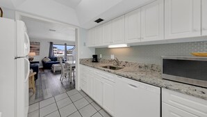 A modern kitchen with white cabinets, a granite countertop, and a built-in oven. - Southbay by the Gulf 60 (Destin)