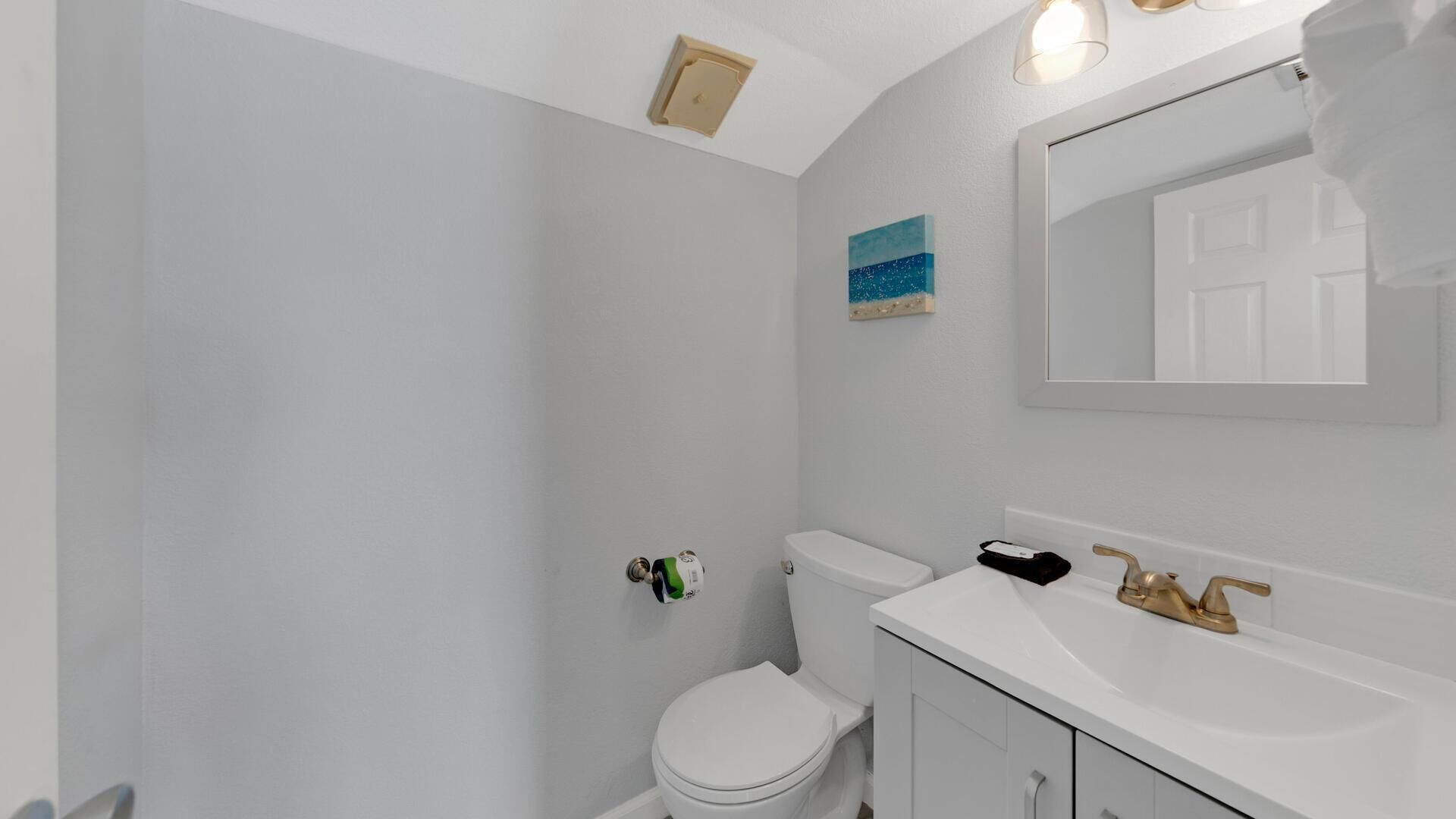 A bathroom with a toilet, sink, and mirror.