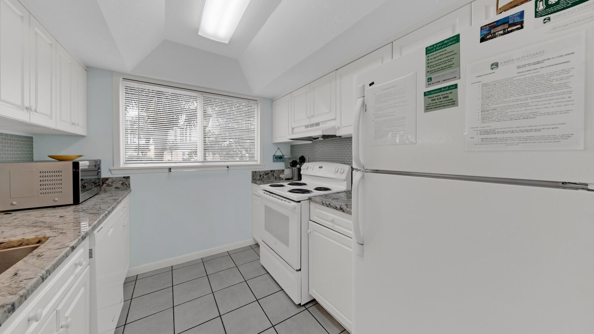 A compact kitchen with white cabinets, a stove, and a refrigerator.