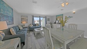A spacious living area with a glass dining table, two sofas, and a ceiling fan. - Southbay by the Gulf 60 (Destin)