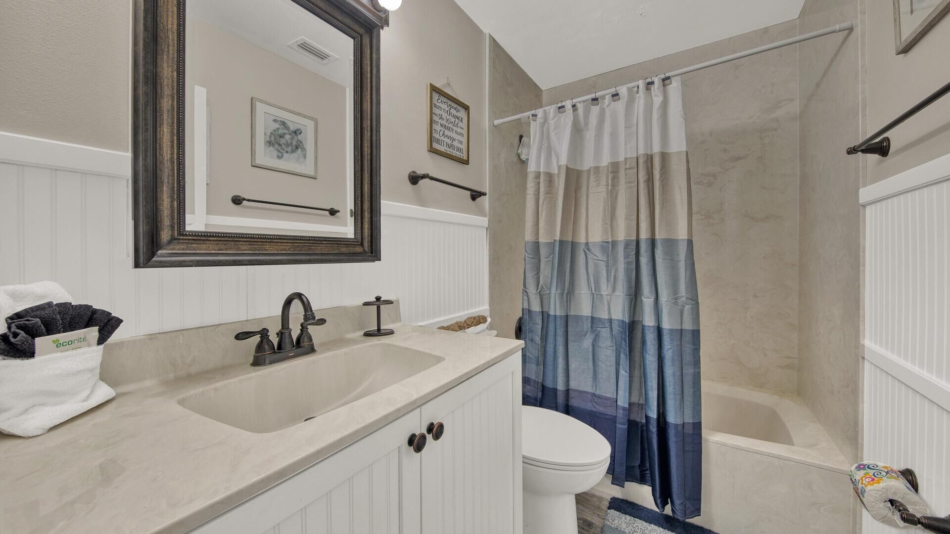 Une salle de bain équipée d’un lavabo, de toilettes et d’un rideau de douche.