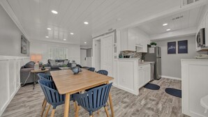 Une cuisine moderne avec des meubles blancs, une table à manger en bois et des chaises bleues.