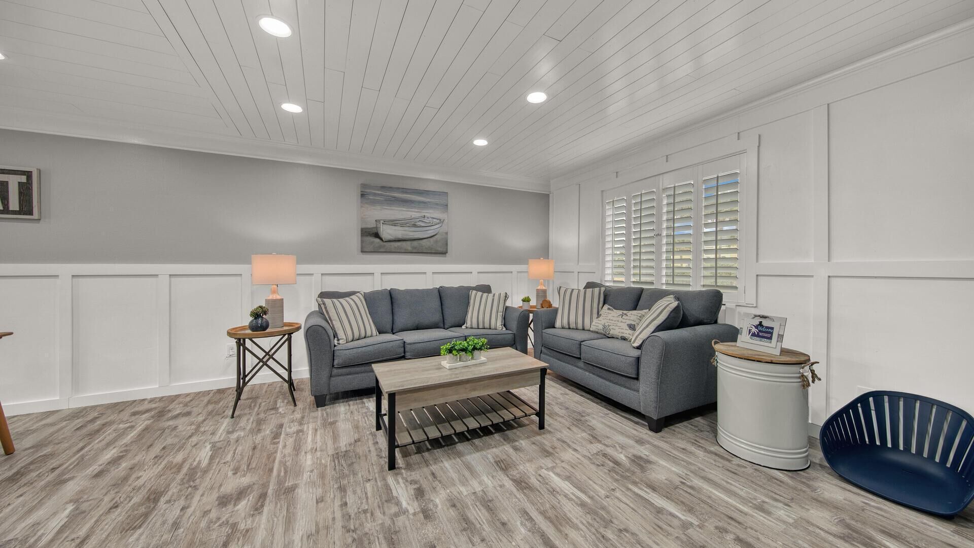 A spacious living room with two grey sofas, a coffee table, and a blue chair.