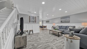 Un salon spacieux avec un escalier, un coin repas et un canapé gris.