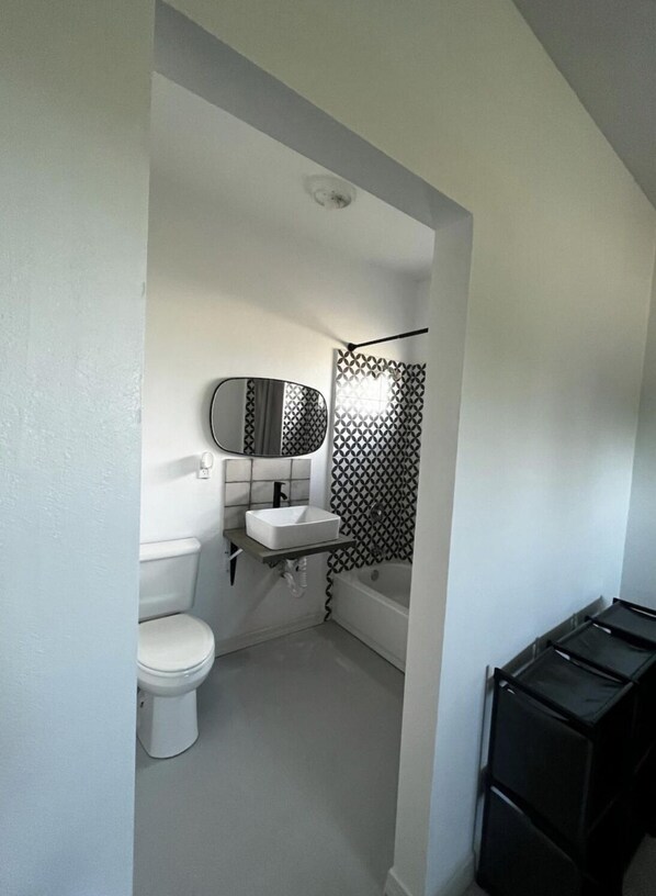 A small, compact bathroom with a toilet, sink, and bathtub. - Furnished apartment in a great country setting. (Blythe)