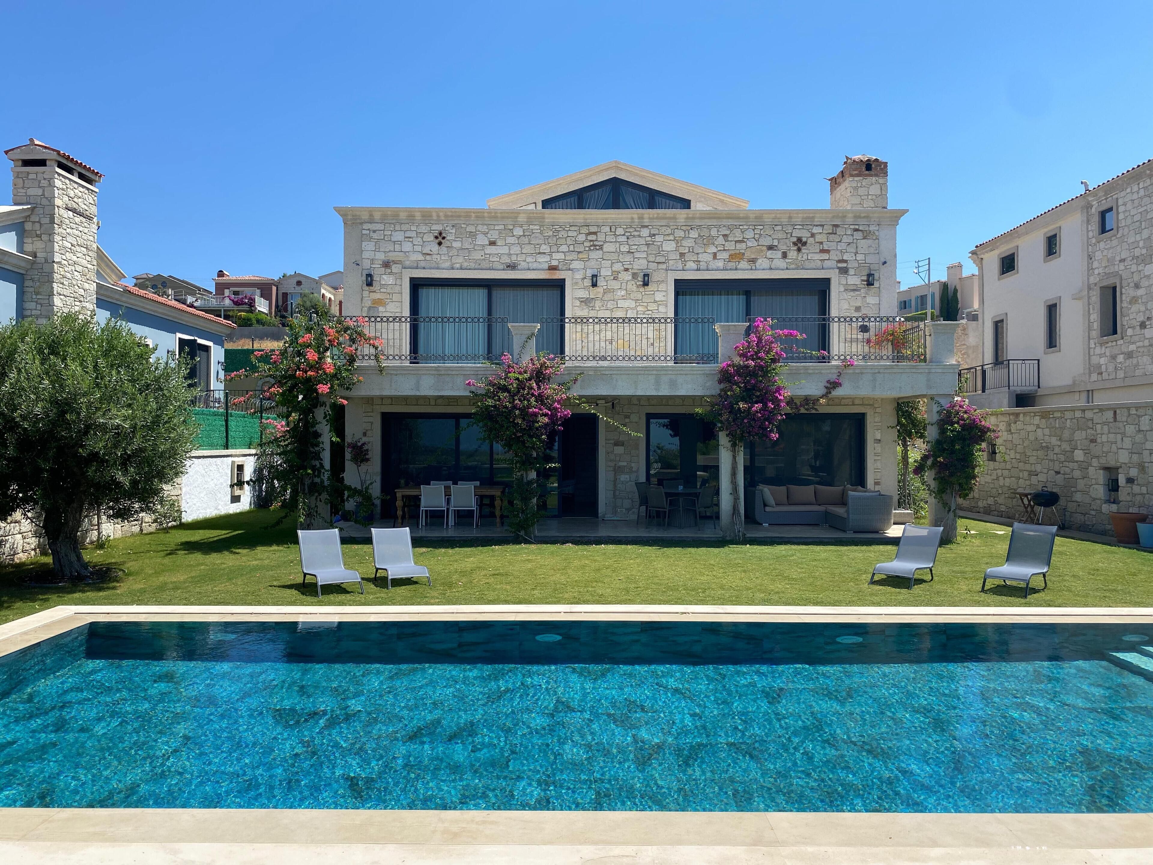 Un edificio in pietra di due piani con una piscina di fronte.
