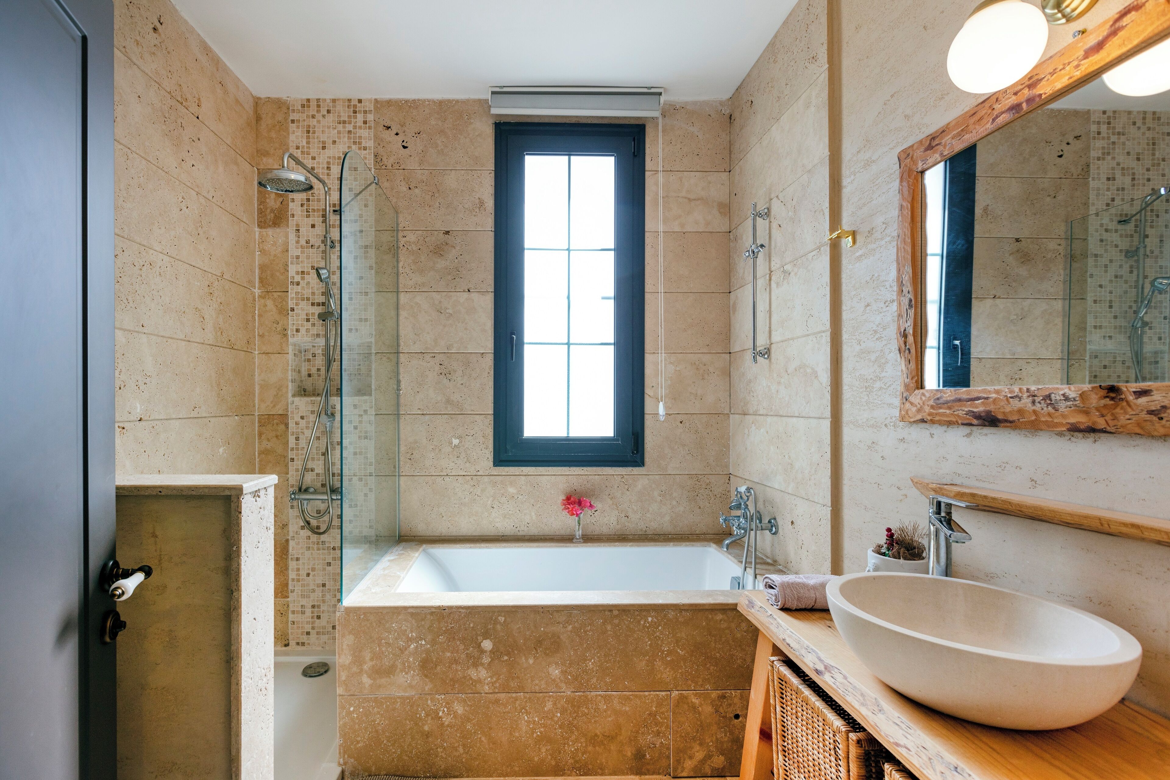 Un baño moderno con una bañera grande, un box de ducha de vidrio y un tocador de madera con un espejo amplio.
