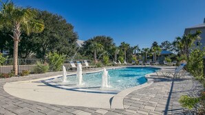 A swimming pool with a fountain, surrounded by lounge chairs and palm trees. - Hidden Lake Condos 113 (Santa Rosa Beach)
